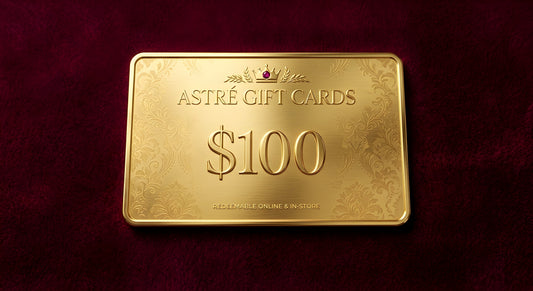 A $100 gold gift card for Astré Gift Cards, featuring an embossed damask pattern and a small crown icon, displayed on a textured dark red background.