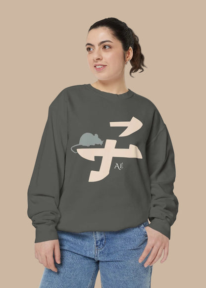 A woman wearing a dark gray crewneck sweatshirt with a beige and gray alien graphic on the front, paired with blue jeans, set against a plain white background.