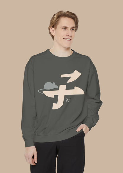 A man wearing a dark gray crewneck sweatshirt with a beige and gray graphic of a mouse inside a stylized character, paired with black pants, against a plain white background.